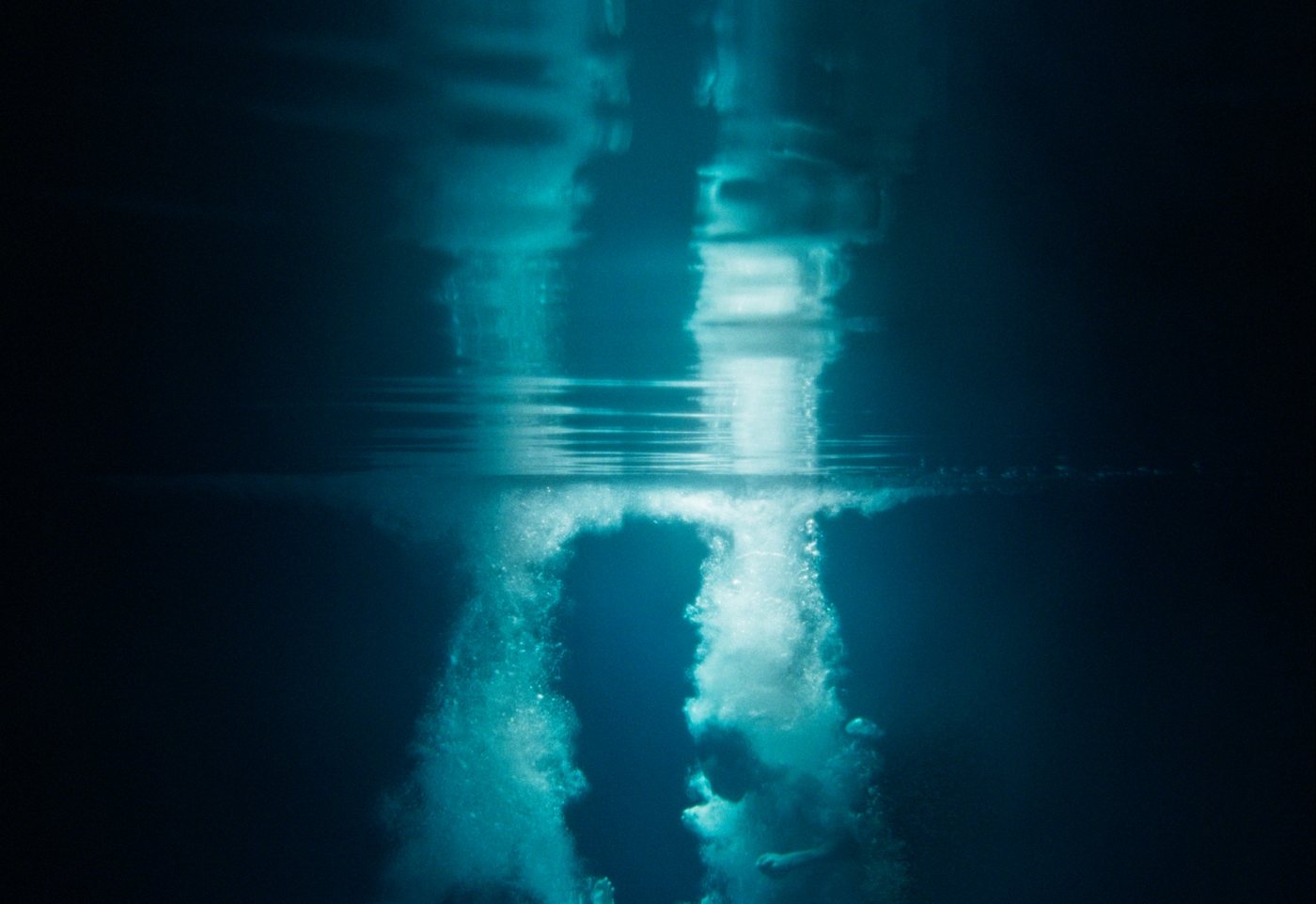 A figure descending beneath the surface of dark water.