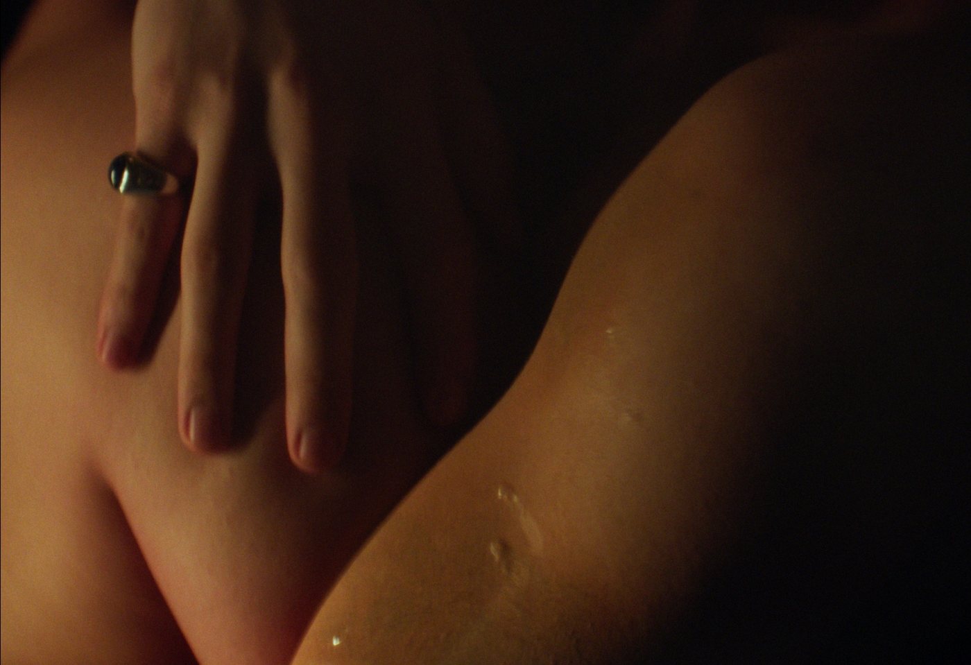 A hand resting on a bare shoulder in warm lamplight.